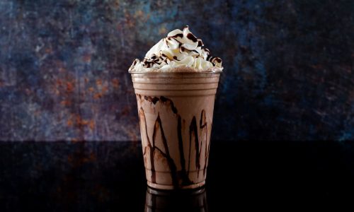 Chocolate milkshake served in a clear glass on a dark background