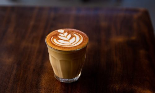 Glass of flat white coffee with heart shaped foam milk